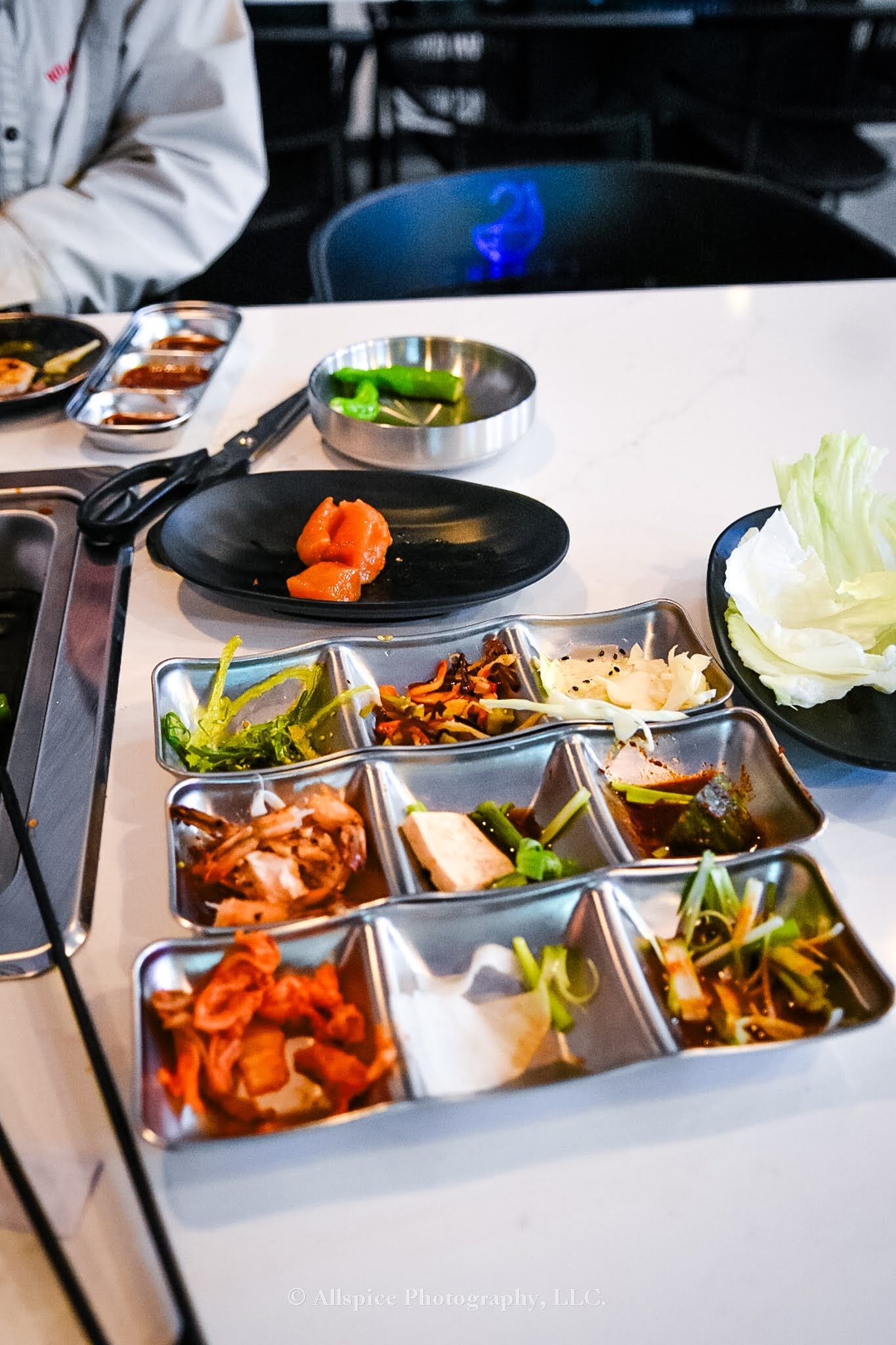 A person is holding chopsticks over a piece of sushi