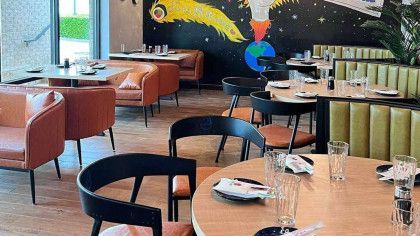 A restaurant with tables and chairs and a mural on the wall.