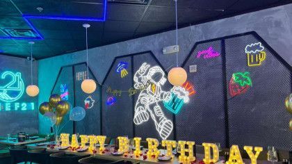 A room decorated for a birthday party with neon lights and balloons.