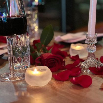 A table with candles roses and a glass of wine