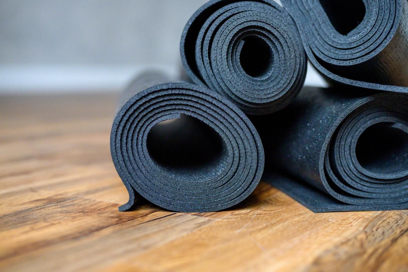 Three Black Yoga Mats Are Stacked On Top Of Each Other On A Wooden Floor — NQPT In Garbutt, QLD