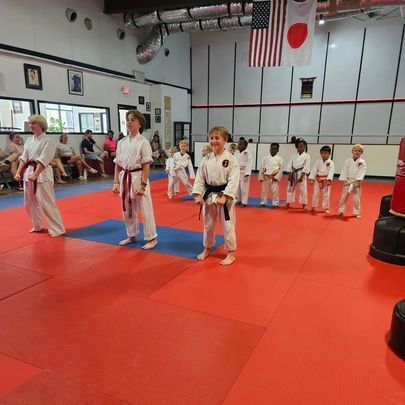 A group of kids are practicing martial arts in a gym