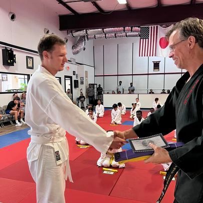 Two men shaking hands in a martial arts gym