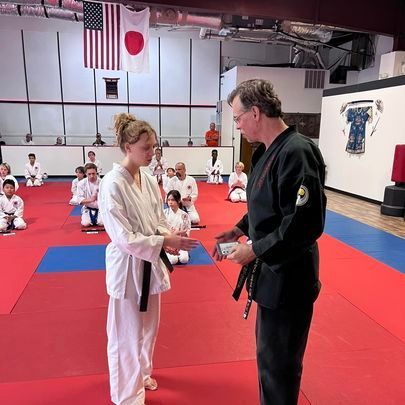 A man and a woman are standing in a gym talking to each other.