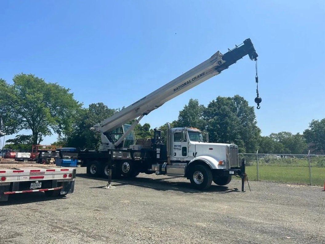 Steel-framed building under construction. Workers on corrugated metal decking, with exposed beams and trusses.
