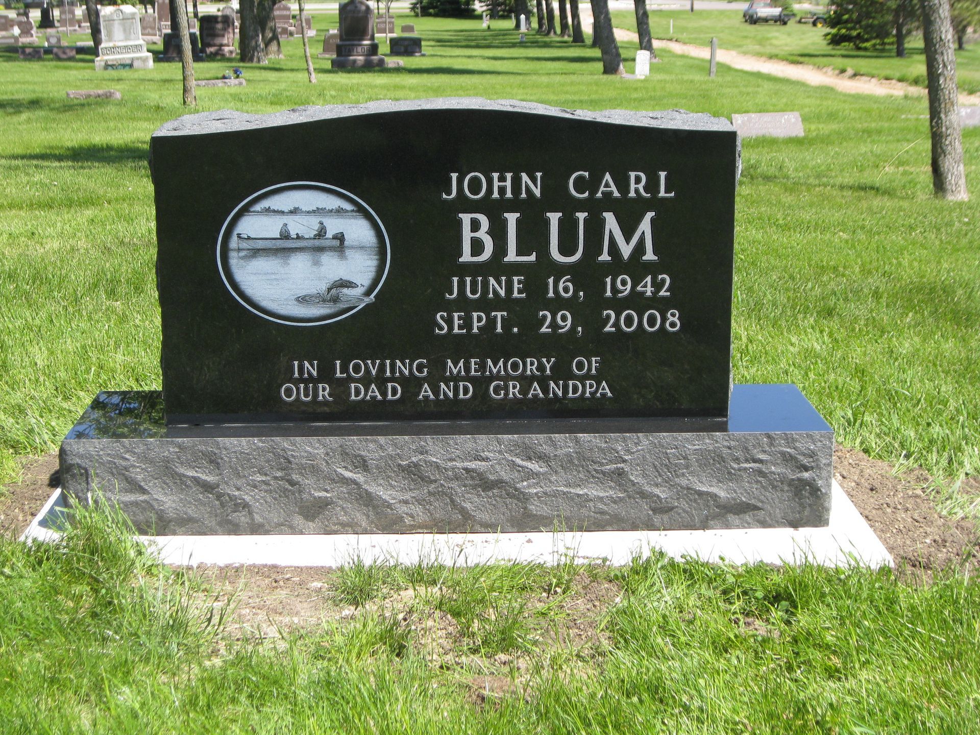 Black headstone with etching and text: