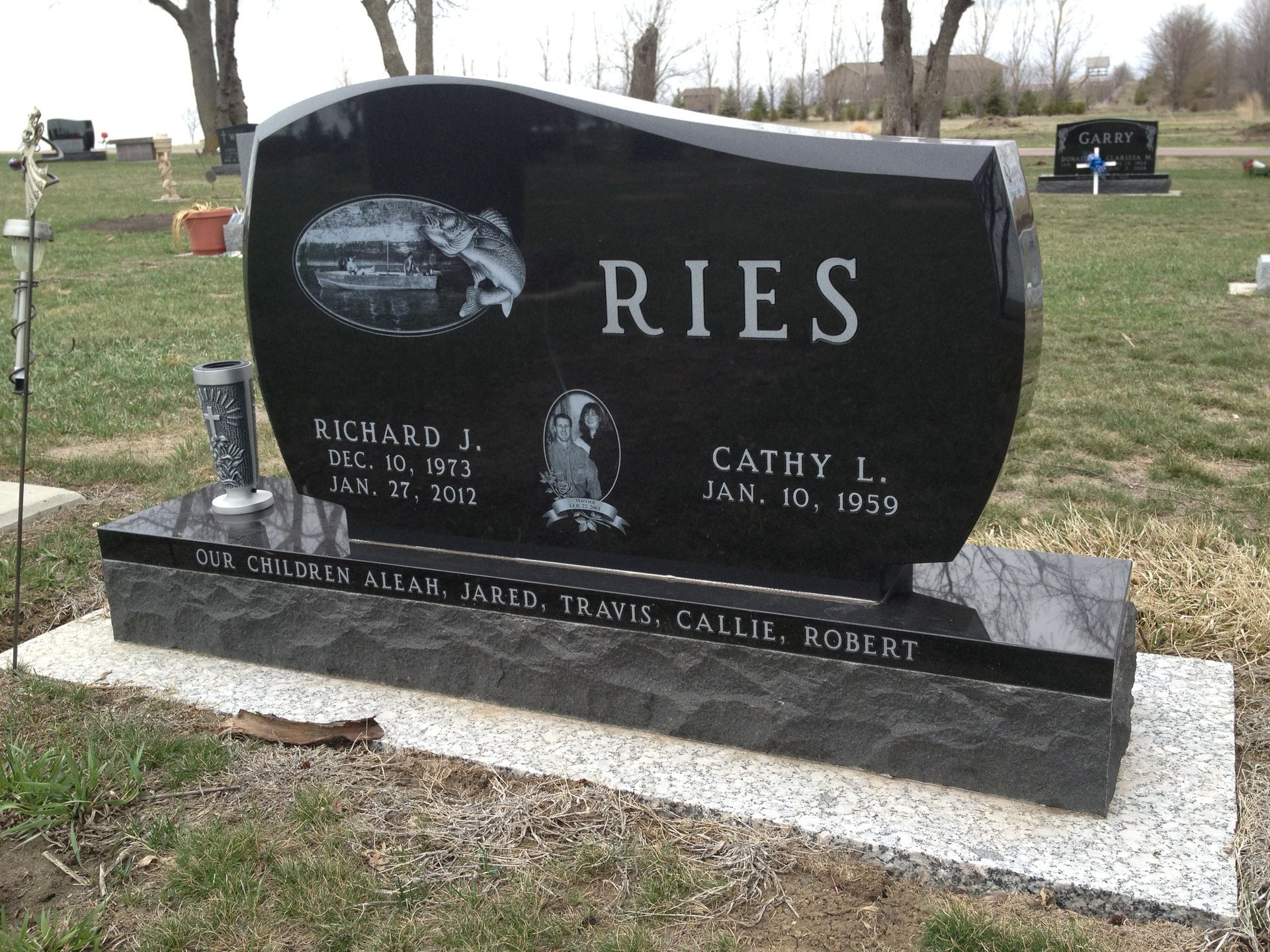 Black granite tombstone with family name Ries and names of Richard and Cathy, with dates.