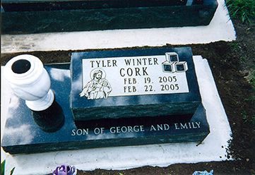 Gravestone for Tyler Winter Cork: black stone, dates Feb. 19, 2005 - Feb. 22, 2005. Includes image, inscribed