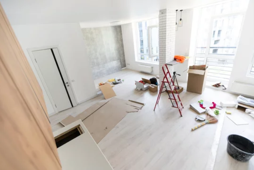 A living room under construction with a ladder and tools on the floor.