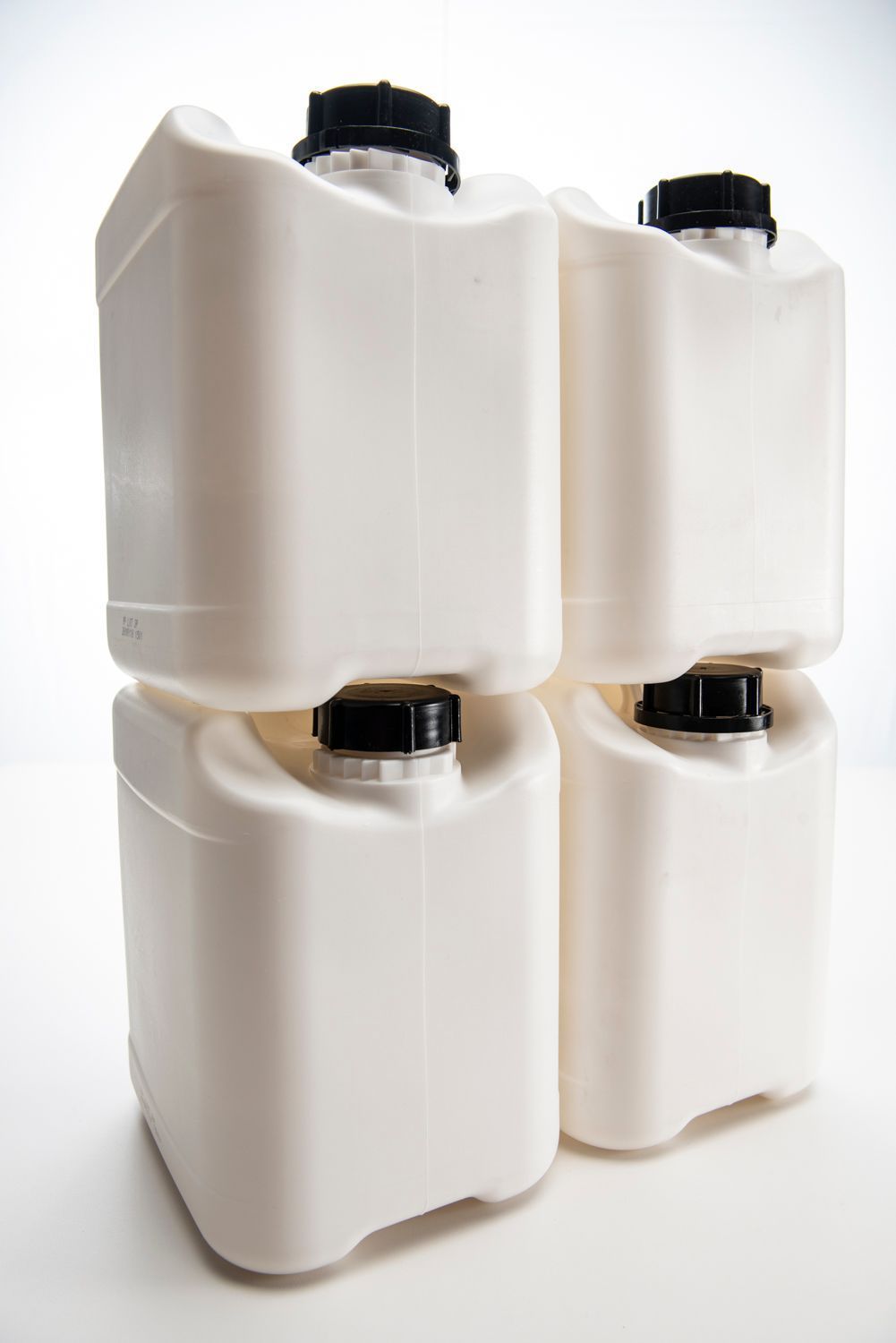 Four white plastic containers are stacked on top of each other on a white surface.