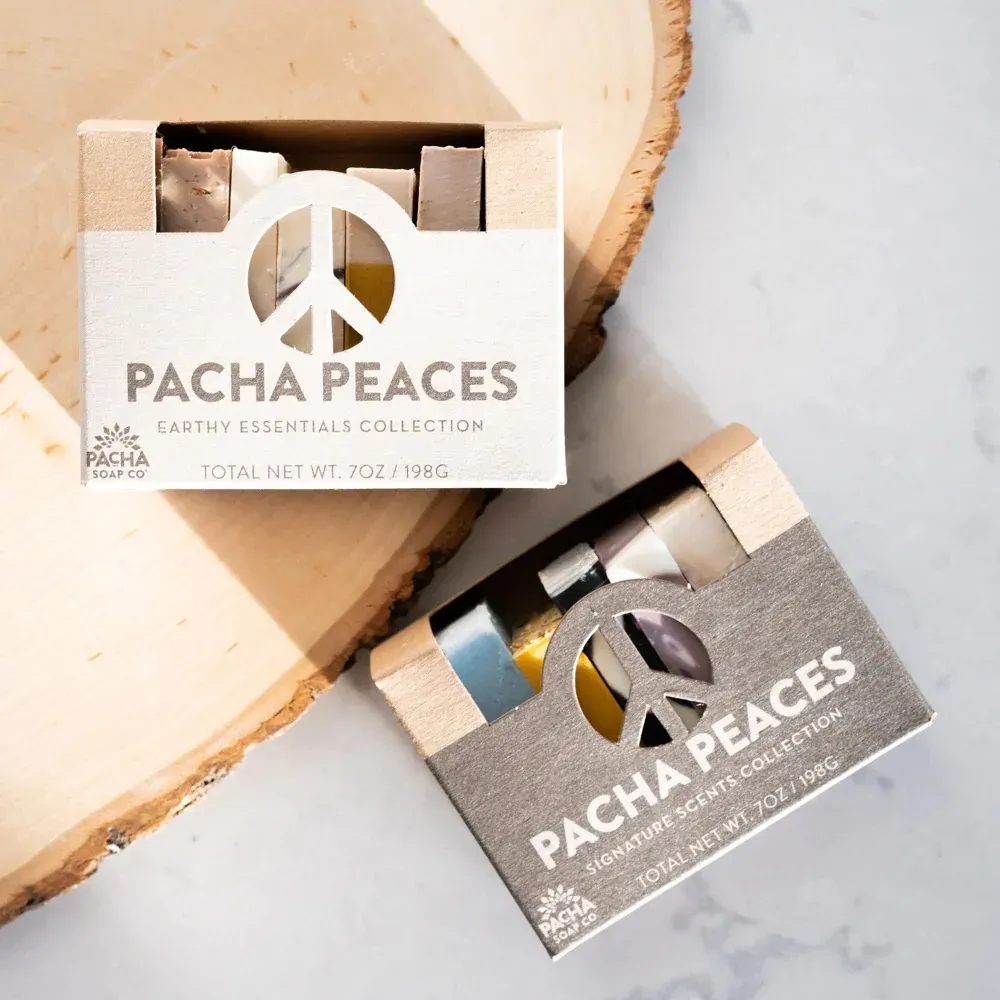 Two boxes of pacha peaces soap are sitting on top of a piece of wood.