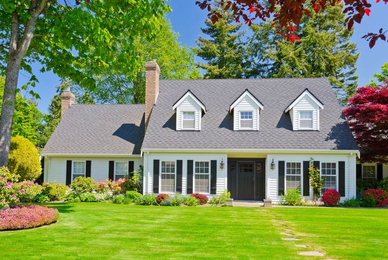 A white house with black shutters and a lush green lawn