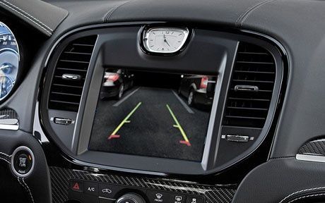 A car dashboard with a clock and a rear view camera
