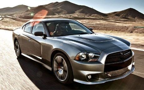 A silver dodge charger is driving down a desert road