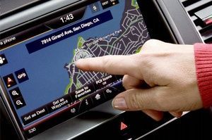 A person is pointing at a map on a car dashboard.