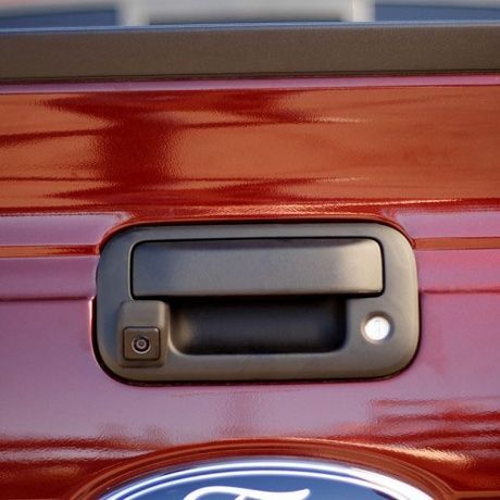 The back of a red ford truck with a black door handle.