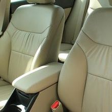 The interior of a car with tan leather seats and a red seat belt.