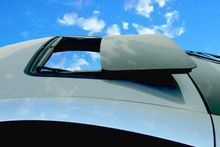A white car with a sunroof and a blue sky in the background.