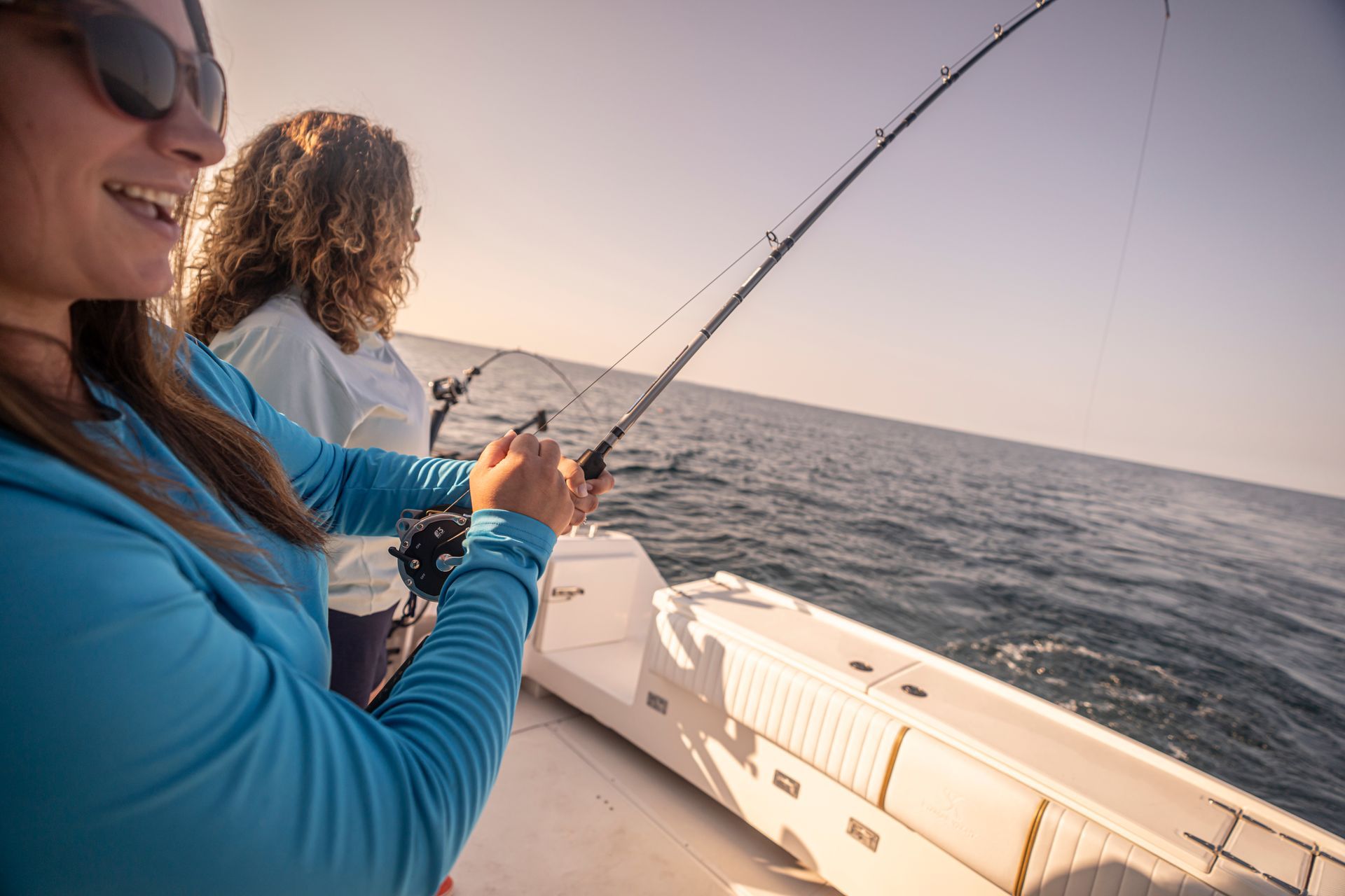 Two women are fishing on a boat in the ocean.