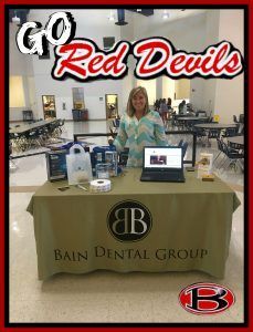 A woman is standing at a table with a laptop on it.