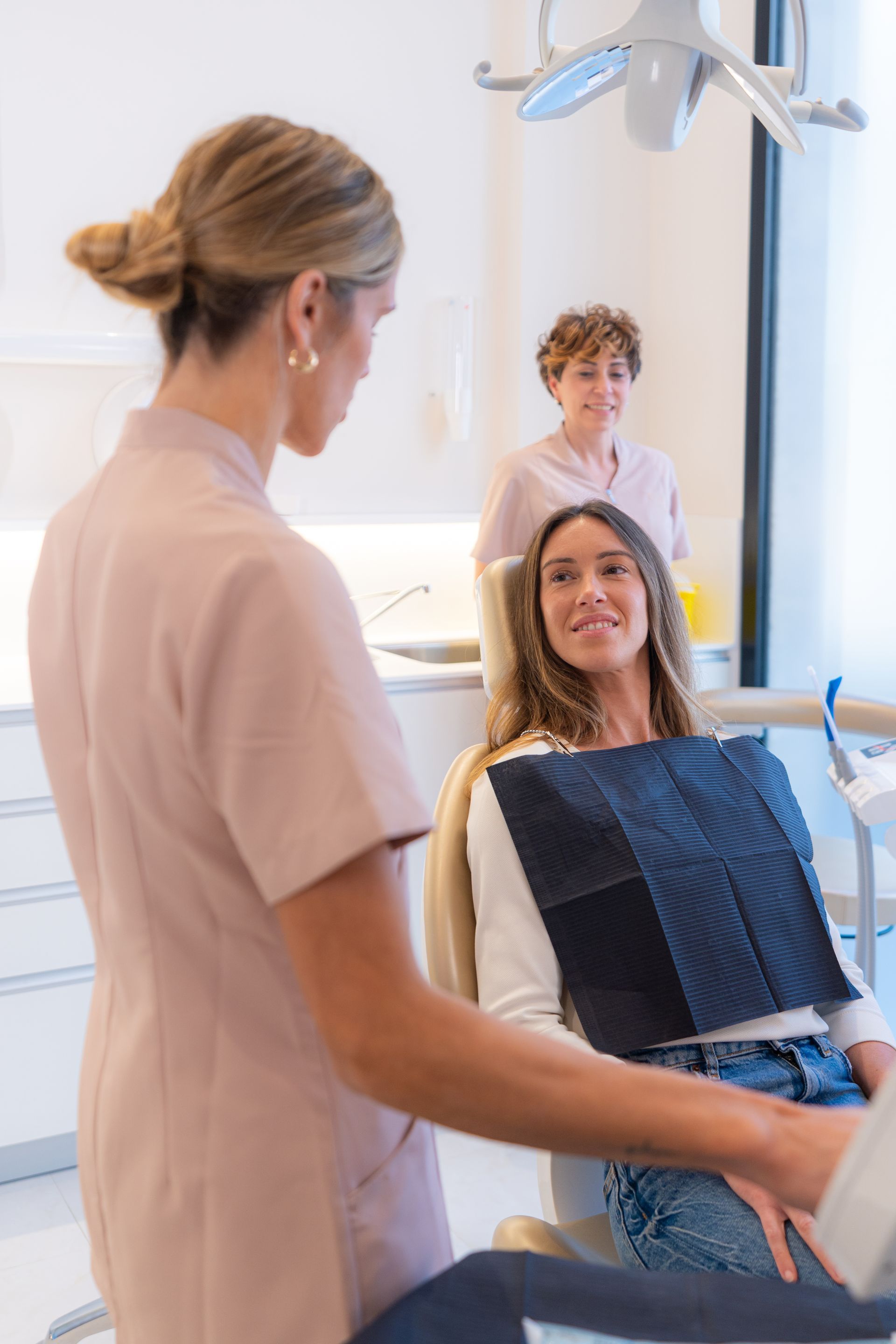 A woman is sitting in a dental chair talking to a dentist.