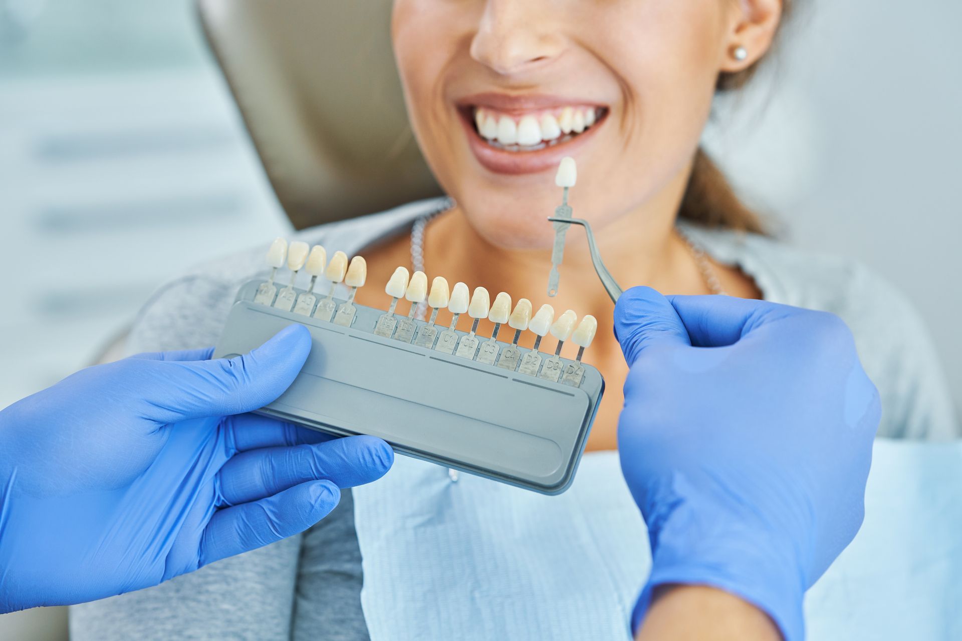 A dentist is holding a tooth color chart in front of a woman 's mouth.