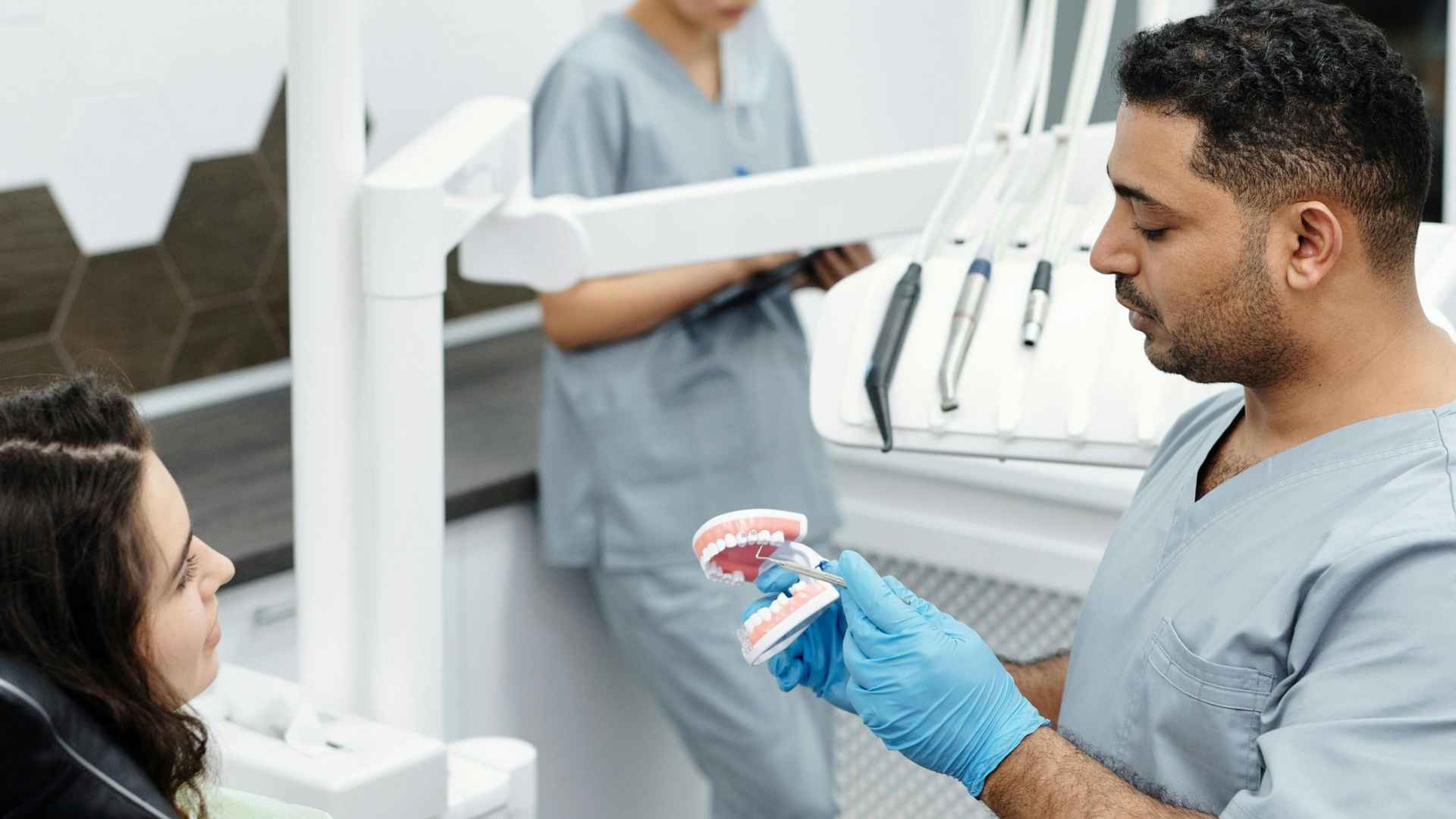 Dentist holding a model of teeth and showing patient details of teeth