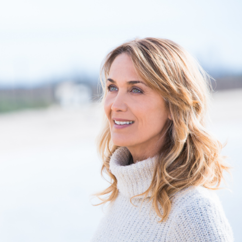 Woman smiling looking in the distance. Woman outside with blurred background.