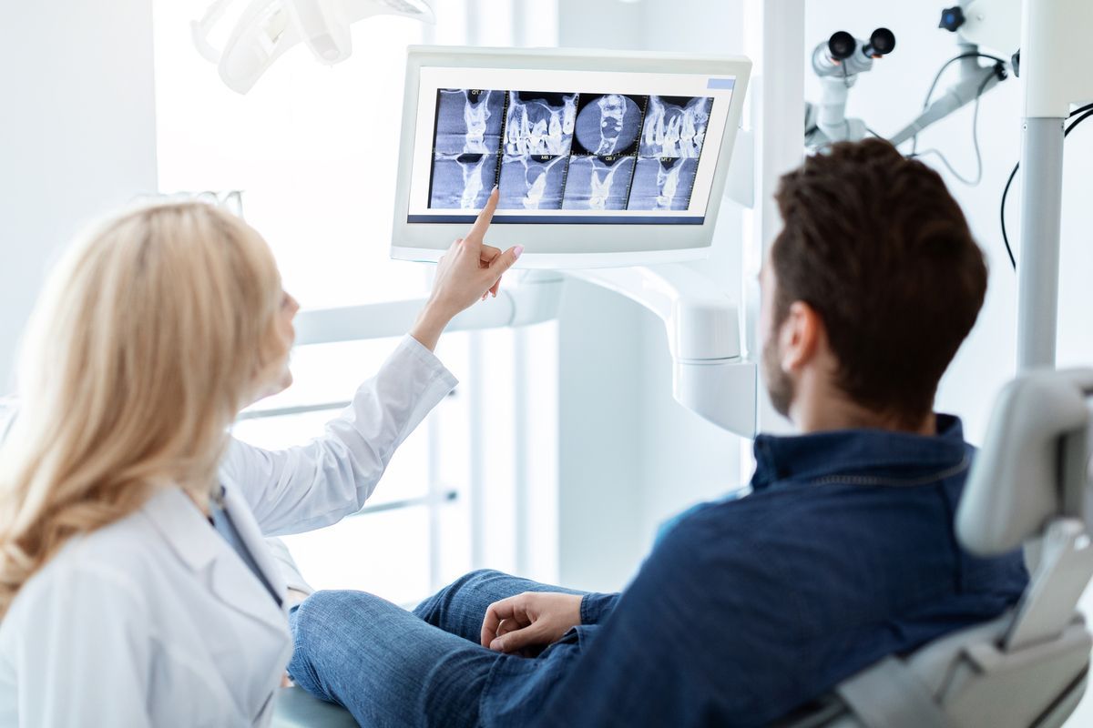 Dentist showing X-ray images to a patient in a bright clinic room