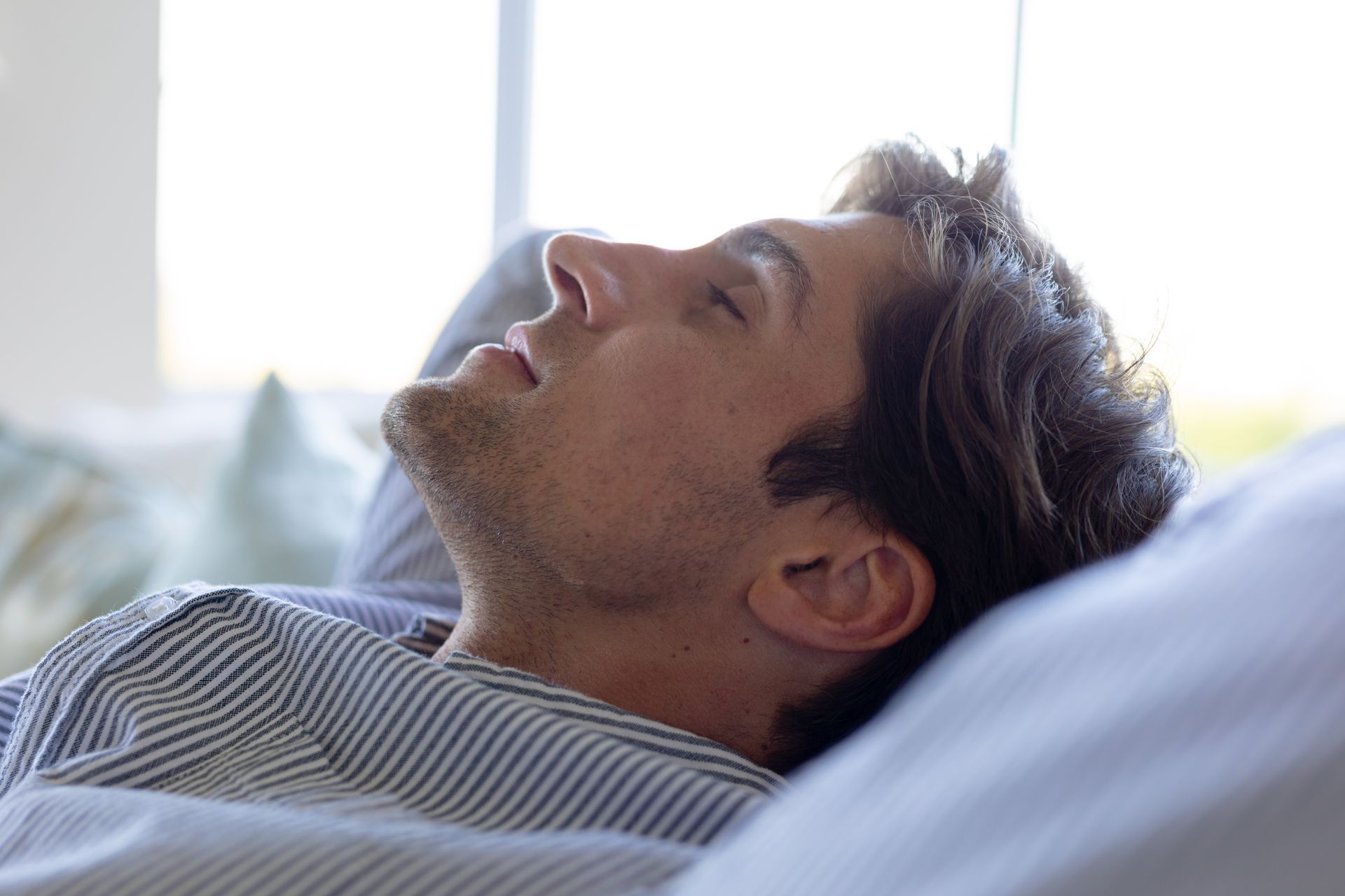 A man is sleeping on a couch with his eyes closed.