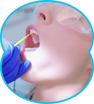 Person's mouth open, dentist in blue glove holding tool, safety glasses worn.