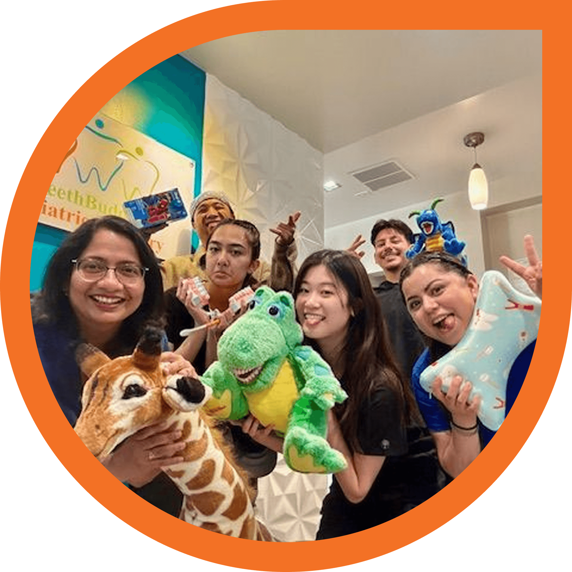 Group of people smiling, holding toys in a dental office.
