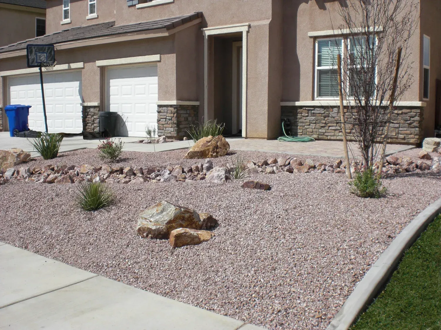 Front yard of a house with gravel, rocks, and sparse landscaping.