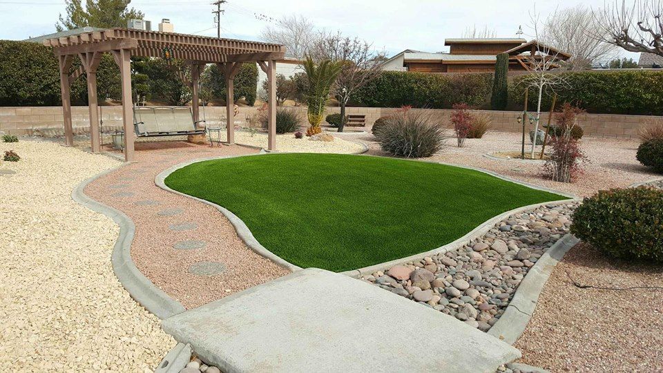 Backyard pond with rocks, water, and greenery, surrounded by grass.