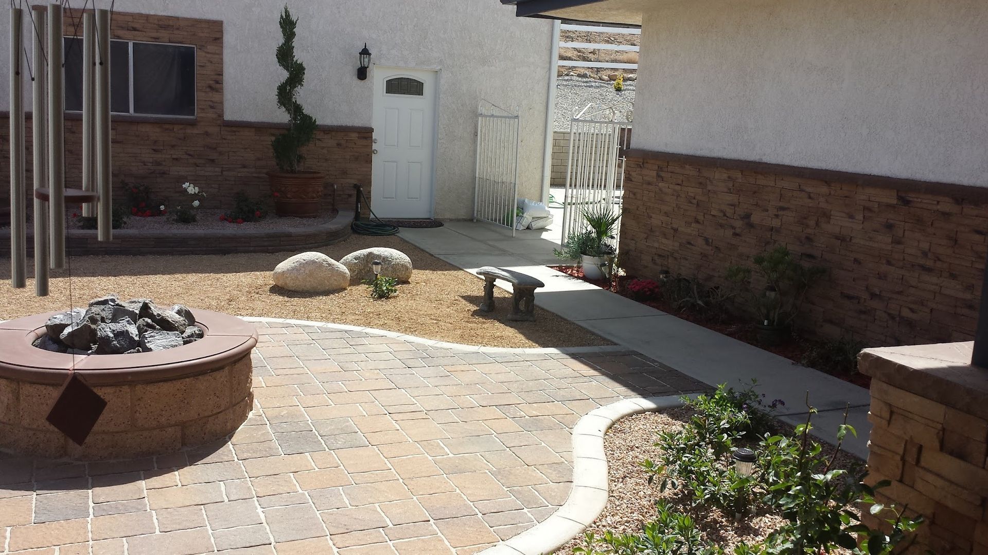 Brick patio with fire pit, walkway, and decorative landscaping.