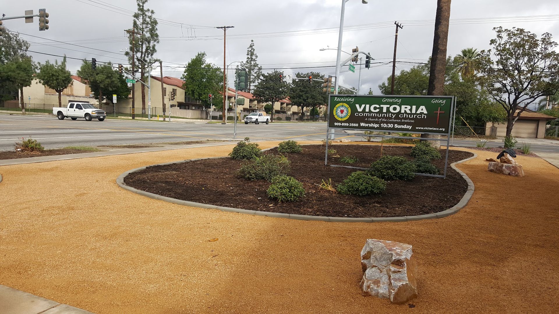 Victoria sign in a landscaped area next to a road, overcast day.