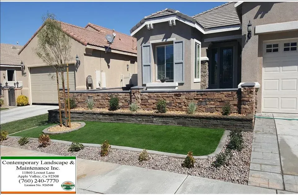 Front yard landscaping with retaining wall, lawn, shrubs, and house.