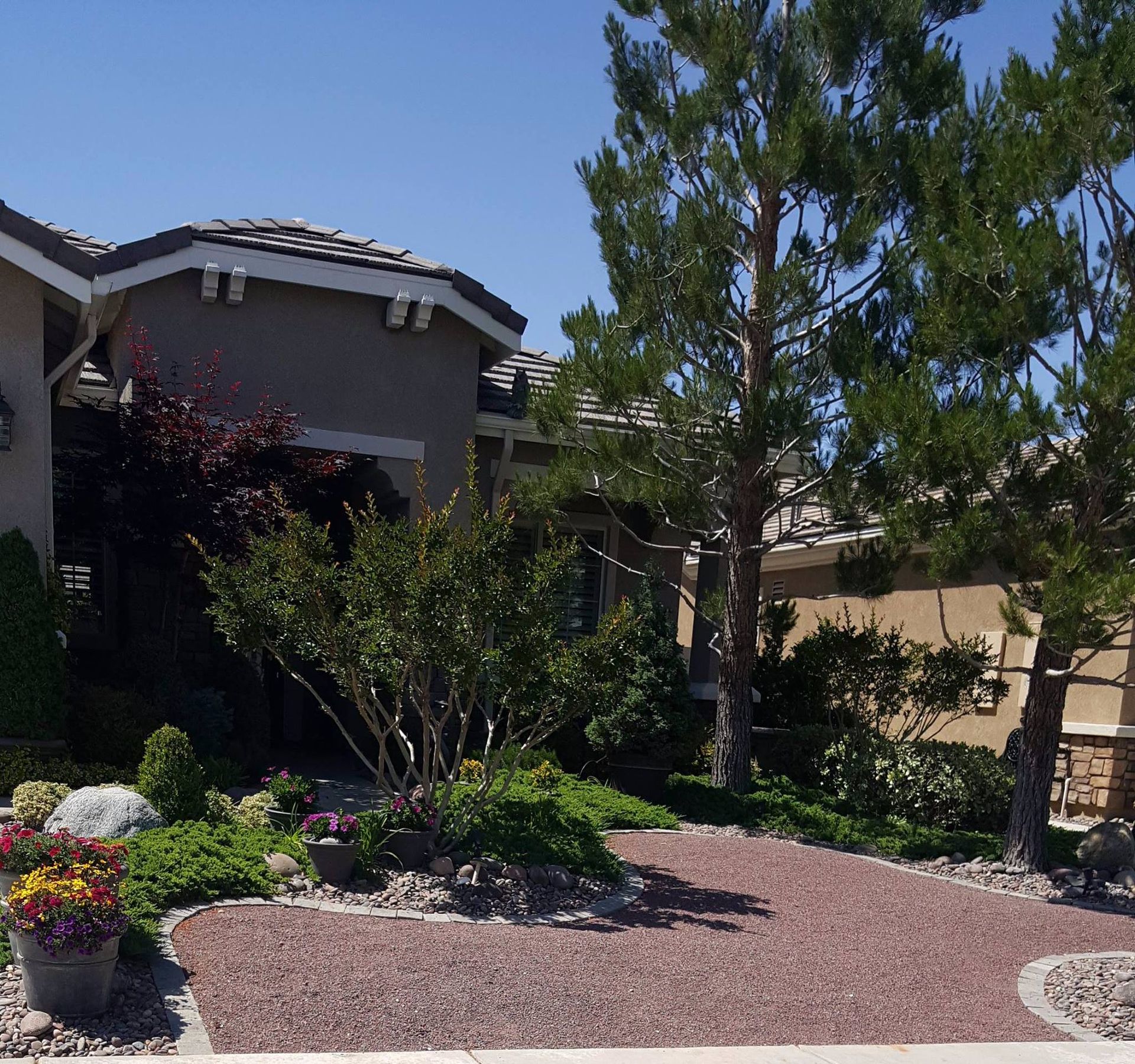 A house with a red gravel driveway and landscaping under a blue sky.