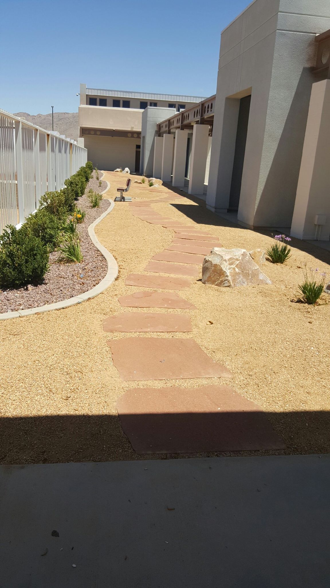Pathway with stepping stones and decorative gravel leading towards buildings.