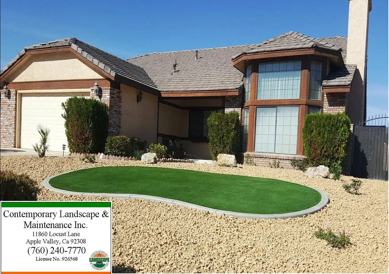 House with front yard landscaping featuring artificial turf and rock bed.