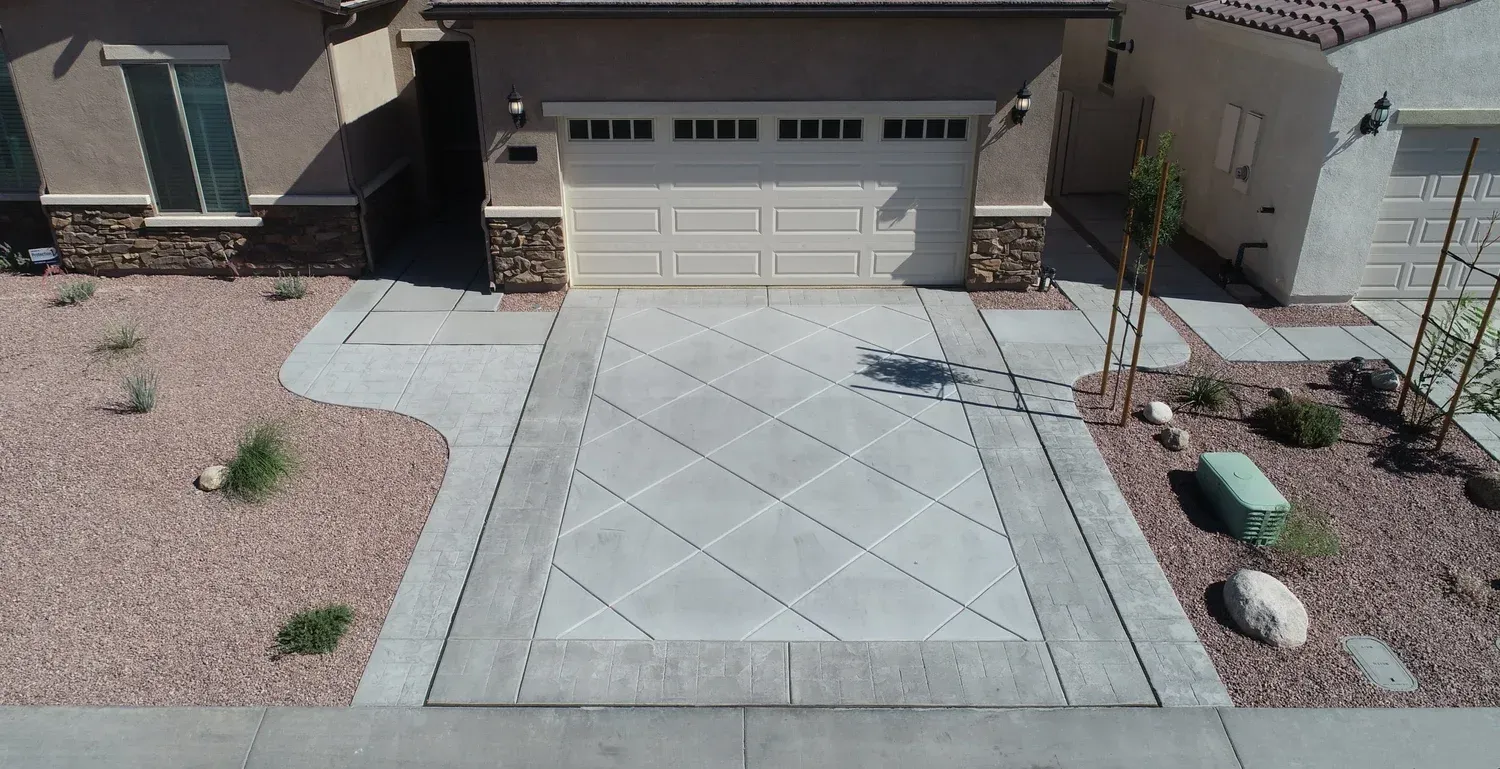 Driveway of a house with decorative concrete, surrounded by landscaping, garage door in center.