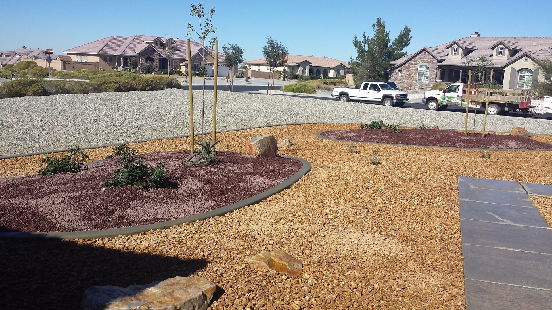 A dry creek bed in a park with a gravel path, rocks, and sparse landscaping, under a sunny sky.