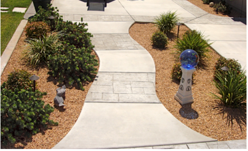 Concrete walkway with landscaping, featuring bushes, gravel, and a decorative globe.