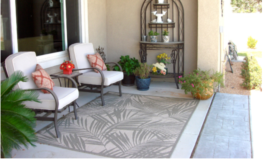 Outdoor seating area with chairs, rug, and decorative table.