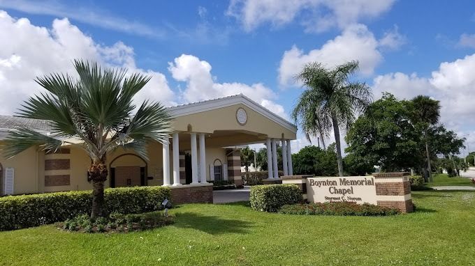 Exterior of the Forest Lawn Memorial Chapel, light yellow building with columns, under blue sky with palm trees.
