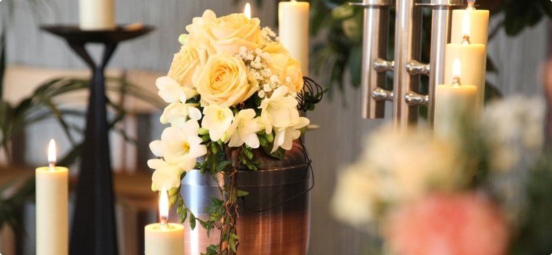 A urn topped with flowers and candles in a church.