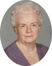 An older woman wearing a purple shirt and pearls