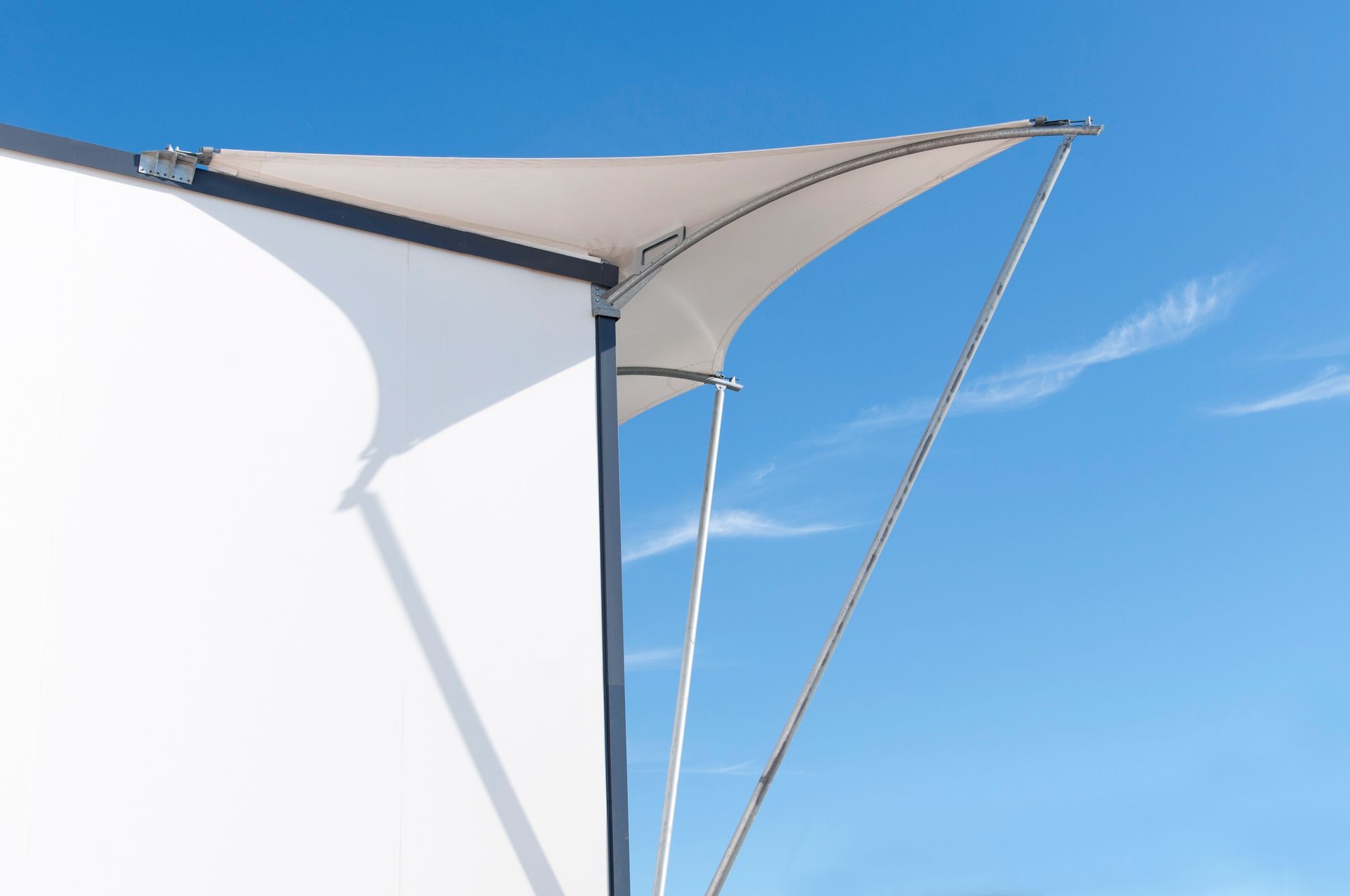 Un paraguas blanco cuelga del costado de un edificio contra un cielo azul.
