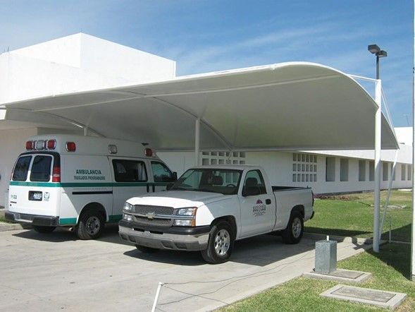 Una ambulancia y un camión estacionados bajo un dosel.