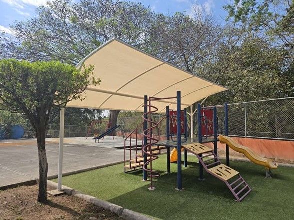 Un parque infantil con tobogán y escaleras bajo un dosel.